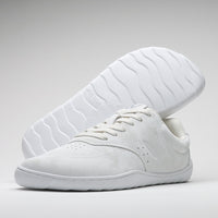 Vaistoa Katu 2 valkoiset paljasjalkasneakerit – minimalistinen, nahkamainen pinta ja tasainen, joustava pohja. Yksi kenkä kuvattuna pohja esillä, Design from Finland -merkintä.