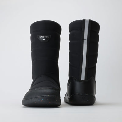 Vaistoa Kinos – lasten korkeavartiset paljasjalkakengät talveen, väri musta. Kuvassa edessä ja takana heijastava nauha, joka lisää näkyvyyttä ja turvallisuutta pimeässä.