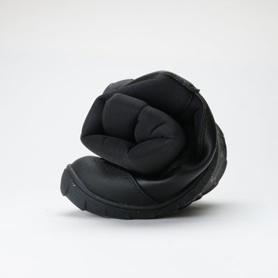 Vaistoa Kinos – lasten korkeavartiset paljasjalkakengät talveen, väri musta. Kuvassa kenkä rullattuna, korostaen ohutta ja joustavaa pohjaa.