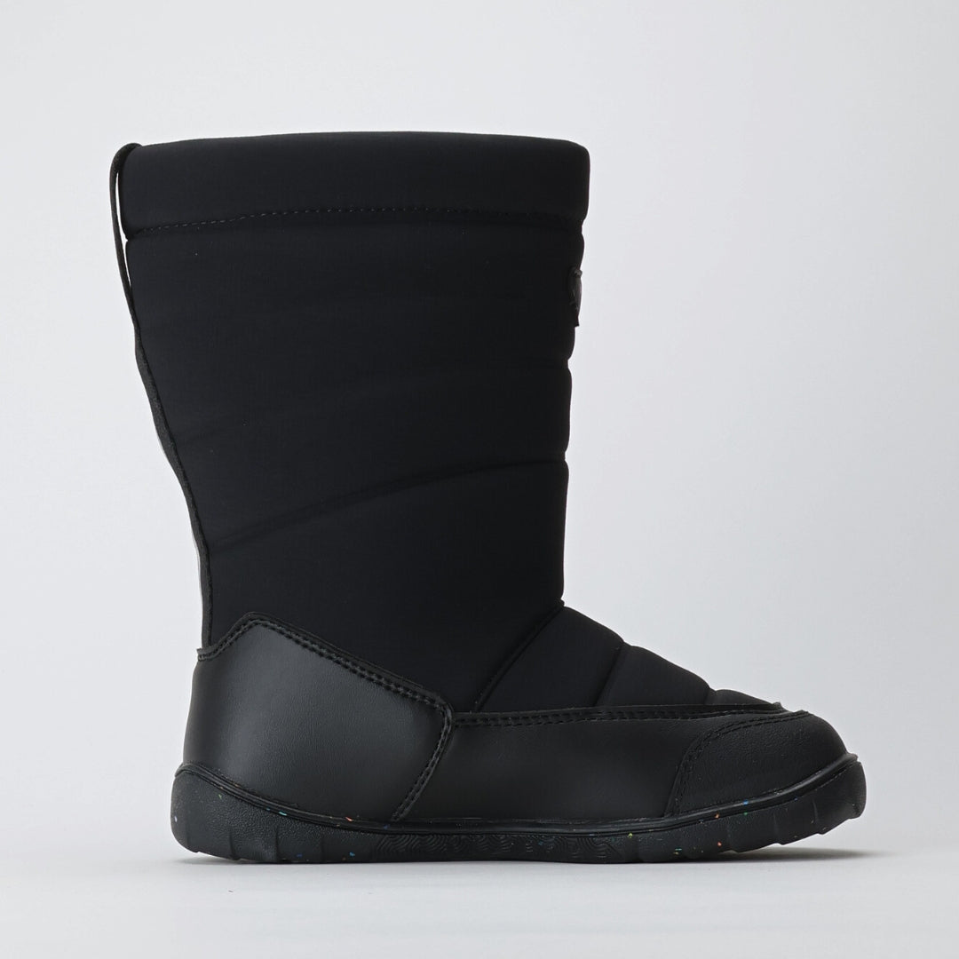 Vaistoa Kinos – lasten korkeavartiset paljasjalkakengät talveen, väri musta. Kuvassa kengän tasainen zero drop -pohja mediaalipuolelta katsottuna, korostaen luonnollista jalkaterän linjaa ja asentoa.